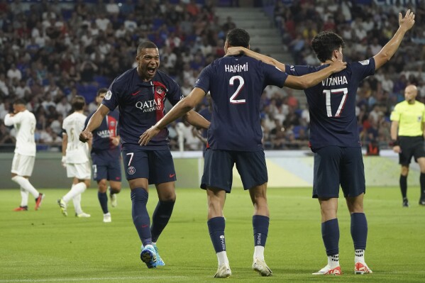 PSG's Achraf Hakimi, centre, celebrates with Vitinha, right, and Kylian Mbappe after scoring his side's second goal during the French League One soccer match between Lyon and Paris Saint-Germain at the Groupama stadium, outside Lyon, France, Sunday, Sept. 3, 2023. (AP Photo/Laurent Cipriani)