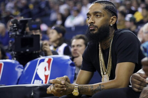 
              FILE - In this March 29, 2018, file photo, rapper Nipsey Hussle watches an NBA basketball game between the Golden State Warriors and the Milwaukee Bucks in Oakland, Calif. Grammy-nominated and widely respected West Coast rapper Nipsey Hussle has been shot and killed outside his Los Angeles clothing store, Los Angeles Mayor Eric Garcetti said Sunday, March 31, 2019. He was 33. (AP Photo/Marcio Jose Sanchez, File)
            