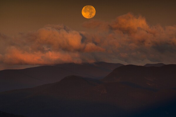 The blue supermoon sets over the White Mountain National Forest at sunrise, Thursday, Aug. 31, 2023, in Carroll County, New Hampshire. (AP Photo/Robert F. Bukaty)
