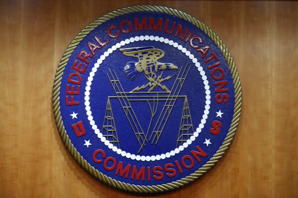 FILE - The seal of the Federal Communications Commission (FCC) is seen before an FCC meeting to vote on net neutrality, Dec. 14, 2017, in Washington. The FCC is announcing that it will outlaw all robocalls featuring AI-generated voices under the existing Telephone Consumer Protection Act. The news comes after celebrities and politicians, including President Joe Biden, have been impersonated using the technology. (APPhoto/Jacquelyn Martin, File)