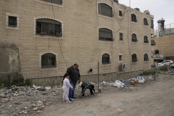 Ali Halhouli and two relatives visit the site where his son Rami Halhouli, 12, was fatally shot by an Israeli police officer while launching a firework last week in Shuafat refugee camp in east Jerusalem, Sunday, March 17, 2024. (AP Photo/Mahmoud Illean)