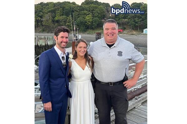This photo provided by the Boston Police Dept., shows from left, Patrick Mahoney, Hannah (Crawford) Mahoney and Boston police officer Joe Matthews on the dock at Thompson Island  in Boston Harbor  on Saturday, Aug. 13, 2022.  Patrick Mahoney was scheduled to get married on Thompson Island, but the boat that was supposed to ferry him to the island where his bride-to-be was waiting broke down.  Officer Matthews transported the groom and his party to the island on his police boat so Mahoney’s marriage to Hannah Crawford could go on as scheduled.(Boston Police Dept. via AP)