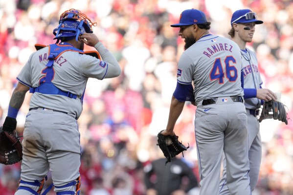 New York Mets pitcher Yohan Ramírez (46) speaks with catcher Omar Narváez (2) at the pitcher's mound after a wild pitch allowed Cincinnati Reds' Jake Fraley (not shown) to reach first base during the eighth inning of a baseball game Saturday, April 6, 2024, in Cincinnati. (AP Photo/Jeff Dean)