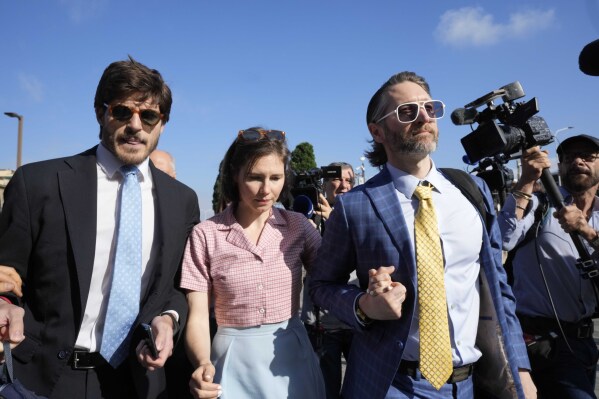 Amanda Knox arrives flanked by her husband Christopher Robinson, right, and her lawyer Luca Luparia Donati at the Florence courtroom in Florence, Italy, Wednesday, June 5, 2024. Amanda Knox returns to an Italian courtroom Wednesday for the first time in more than 12½ years to clear herself "once and for all" of a slander charge that stuck even after she was exonerated in the brutal 2007 murder of her British roommate in the idyllic hilltop town of Perugia. (AP Photo/Antonio Calanni)
