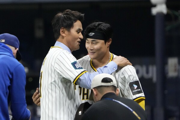 Former Major League Baseball pitcher Chan Ho Park, left, hugs San Diego Padres' Ha-Seong Kim after throwing out the ceremonial first pitch prior to an opening day baseball game between the Padres and the Los Angeles Dodgers at the Gocheok Sky Dome in Seoul, South Korea Wednesday, March 20, 2024, in Seoul, South Korea. (AP Photo/Ahn Young-joon)