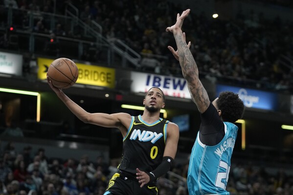 Indiana Pacers' Tyrese Haliburton (0) shoots against Charlotte Hornets' P.J. Washington (25) during the first half of an NBA basketball game Wednesday, Dec. 20, 2023, in Indianapolis. (AP Photo/Darron Cummings)