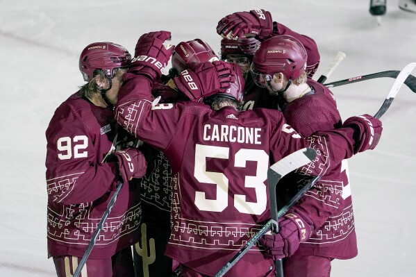 Arizona Coyotes' Michael Carcone (53) gets mobbed by teammates after scoring his third goal for a hat-trick against the Chicago Blackhawks during the second period of an NHL hockey game Monday, Oct. 30, 2023, in Tempe, Ariz. (AP Photo/Darryl Webb)