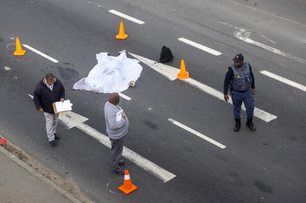 A covered corpse lays in a road on the outskirts of Cape Town, South Africa, Tuesday, Aug. 7, 2023. Two people were fatally shot on a fifth day of violent protests in sparked by a dispute last week between minibus taxi drivers and authorities. The unrest on the outskirts of South Africa’s second-largest city follows an announcement last Thursday of a weeklong strike by minubus taxi drivers angered at what they call heavy-handed tactics by police and city authorities. (AP Photo)