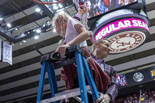 Alabama coach Nate Oats holds up the net after he and his daughter Brielle cut the final strand of it, as Alabama clinched the regular-season Southeastern Conference title with an overtime time win against Auburn in an NCAA college basketball gameWednesday, March 1, 2023, in Tuscaloosa, Ala. (AP Photo/Vasha Hunt)