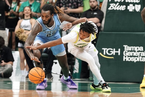 Tulane guard Jaylen Forbes (25) steals the ball from South Florida guard Jayden Reid (0) during the first half of an NCAA college basketball game Tuesday, March 5, 2024, in Tampa, Fla. (AP Photo/Chris O'Meara)
