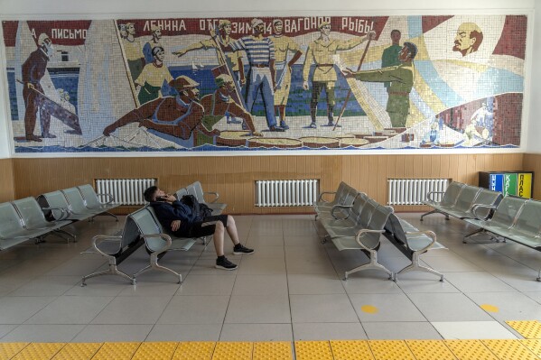 A man waits for a train at the Aralsk city train station under a mural from the Soviet era, in Kazakhstan, Tuesday, July 4, 2023. (APPhoto/Ebrahim Noroozi)