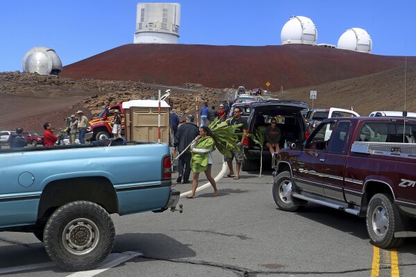 FILE - In this Oct. 7, 2014 photo, protesters block vehicles from getting to the Thirty Meter Telescope groundbreaking ceremony site at Mauna Kea, Hawaii. The National Science Foundation has launched an informal outreach to Hawaii about possible funding efforts for the stalled Thirty Meter Telescope project. The Honolulu Star-Advertiser reported the effort by the nation's top funder of basic research could lead to a huge influx of cash for the astronomy project on Mauna Kea with an estimated cost of $2.4 billion. Telescope opponents who demonstrated for months say the project on the state's tallest mountain would desecrate land considered sacred by some Native Hawaiians. (Hollyn Johnson/Hawaii Tribune-Herald via AP, File)