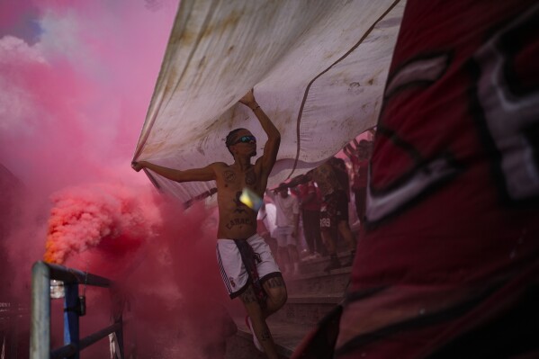 Caracas FC fan club members who call themselves The Red Demons wave flags and flares during a local league soccer match against Deportivo Tachira in Caracas, Venezuela, Sunday, March 3, 2024. (AP Photo/Matias Delacroix)