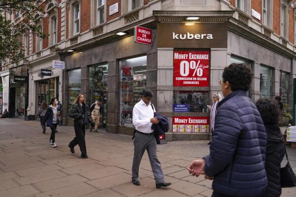 People walk past a bureau de change, in London, Wednesday, Oct. 12, 2022. The pound sank against the dollar early Wednesday after the Bank of England governor confirmed the bank won't extend an emergency debt-buying plan introduced last month to stabilize financial markets. (AP Photo/Alberto Pezzali)