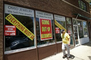 FILE - A man walks past a retail store that is going out of business due to the coronavirus pandemic in Winnetka, Ill., Tuesday, June 23, 2020. More than 1.4 million laid-off Americans applied for unemployment benefits last week, reported Thursday, July 30, further evidence of the devastation the coronavirus outbreak has unleashed on the U.S. economy. (AP Photo/Nam Y. Huh)