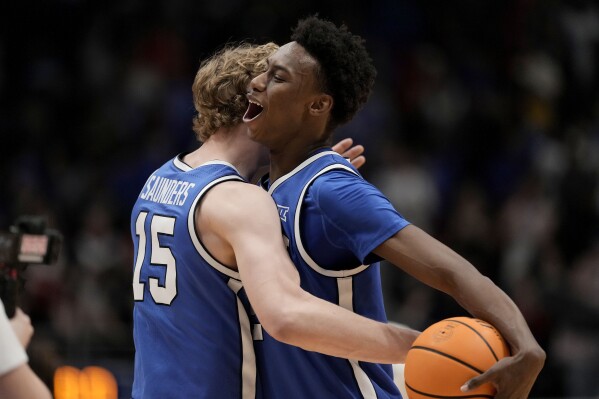 BYU guards Jaxson Robinson, right, and Richie Saunders (15) hug after their NCAA college basketball game against Kansas Tuesday, Feb. 27, 2024, in Lawrence, Kan. BYU won 76-68. (AP Photo/Charlie Riedel)