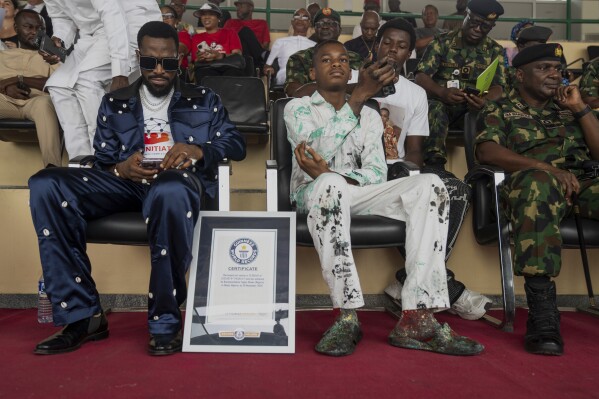 Kanyeyachukwu Tagbo-Okeke, Centre, a 15 year-old autistic artist who won the Guinness World Record for the largest art canvas, attends the World Autism Day in Abuja, Nigeria, Wednesday, April 2, 2025. (AP Photo/David Durowaiye)