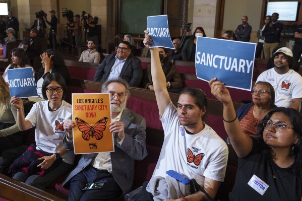 Members of immigration advocacy groups react as Los Angeles City Council votes to enact an ordinance to prohibit city resources from being used for immigration enforcement in anticipation of potential mass deportations under President-elect Donald Trump, inside Los Angeles City Hall on Tuesday, Nov. 19, 2024. (AP Photo/Damian Dovarganes, File)