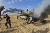 Palestinians celebrate by a destroyed Israeli tank at the Gaza Strip fence east of Khan Younis southern Saturday, Oct. 7, 2023. The militant Hamas rulers of the Gaza Strip carried out an unprecedented, multi-front attack on Israel at daybreak Saturday, firing thousands of rockets as dozens of Hamas fighters infiltrated the heavily fortified border in several locations by air, land, and sea and catching the country off-guard on a major holiday. (AP Photo)