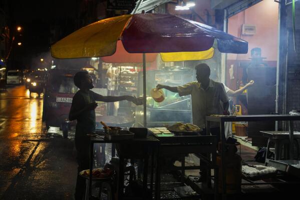 A street vendor sells food in Colombo, Sri Lanka, Wednesday, Dec. 28, 2022. In Sri Lanka, where the tourism-driven economy also has been hammered by political upheavals and shortages, the situation remains dire since COVID-19 hit in early 2020. (AP Photo/Eranga Jayawardena)