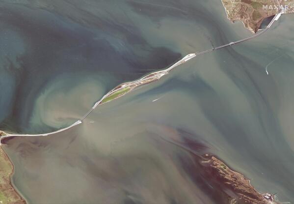 This satellite image provided by Maxar Technologies shows damage to the Kerch Bridge, which connects the Crimean Peninsula, top right, with Russia, bottom left, crossing a strait between the Black Sea and the Sea of Azov, and rail cars on fire, upper right, on Saturday, Oct. 8, 2022. North is towards the right. (Maxar Technologies via AP)