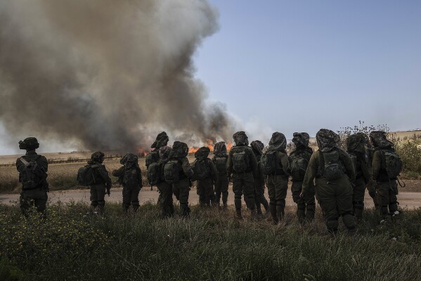 FILE - Israeli soldiers watch a wheat field burn next to Kibbutz Nahal Oz along the Israel-Gaza border, May 14, 2018. (AP Photo/Tsafrir Abayov)