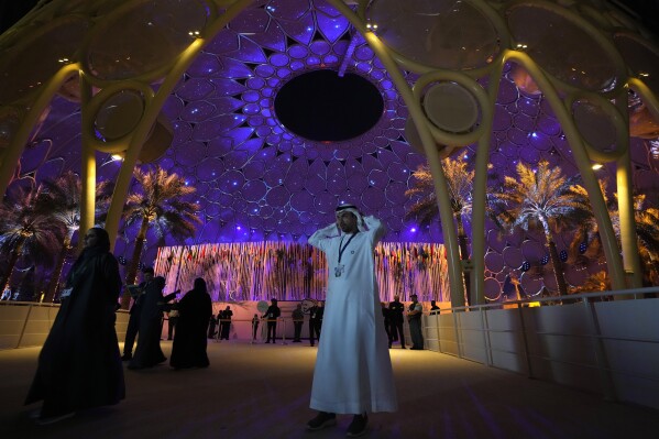 People walk near a lit up Al Wasl Dome at Expo City at the COP28 U.N. Climate Summit, Dec. 1, 2023, in Dubai, United Arab Emirates. (AP Photo/Peter Dejong)