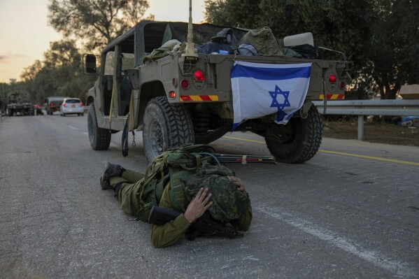An Israeli soldier mistakenly thinks he hears an air raid siren and jumps to the ground to take cover in kibbutz Be'eri, Israel, Wednesday, Oct. 11, 2023. The kibbutz was overrun by Hamas militants from Neraby Gaza Strip Saturday when they killed and captured many Israelis. (AP Photo/Ohad Zwigenberg)