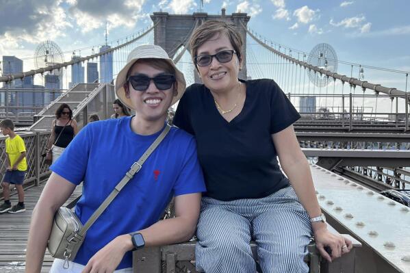 In this photo provided by Leah Bustamante Laylo, John Albert Laylo, left, poses with her mother Leah Bustamante Laylo during their vacation at Brooklyn Bridge in New York City on June 13, 2022. The mayor of Philadelphia expressed shock and sorrow over the killing of Filipino lawyer, John Albert Laylo, who was shot in the city over the weekend and is offering a $20,000 reward for information that will lead to the arrest of the shooter, a senior Philippine diplomat said Wednesday. Laylo and his mother were heading to the airport to board a flight early Saturday when the incident happened. (Courtesy of Leah Bustamante Laylo via AP)
