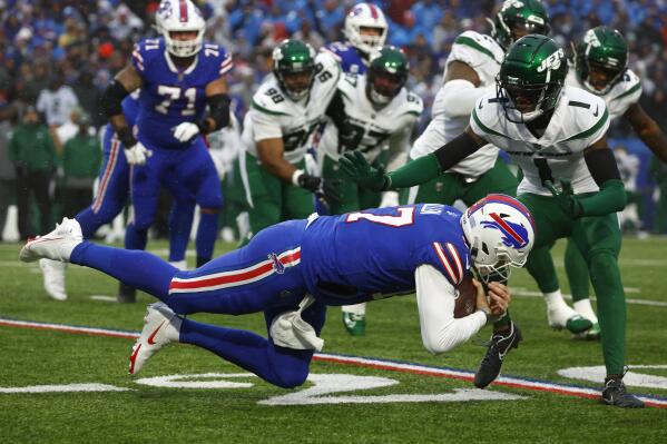 Buffalo Bills quarterback Josh Allen, front, lunges with the ball under pressure from New York Jets cornerback Sauce Gardner (1) during the first half of an NFL football game, Sunday, Dec. 11, 2022, in Orchard Park, N.Y. (AP Photo/Jeffrey T. Barnes)