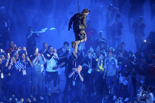 Tom Cruise is lowered on the Stade de France during the 2024 Summer Olympics closing ceremony, Sunday, Aug. 11, 2024, in Saint-Denis, France. (AP Photo/Kin Cheung)