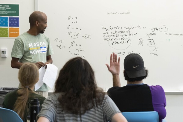 George Mason Term Instructor Ermias Kassaye, standing left, leads a summer math boot camp on Thursday, Aug. 1, 2023 at George Mason University in Fairfax. Va. Dozens opted to spend a week of summer break at the university brushing up on math lessons that didn’t stick during pandemic schooling. The northern Virginia school started Math Boot Camp because of alarming numbers of students arriving with gaps in their math skills. (AP Photo/Kevin Wolf)