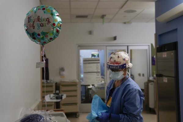 FILE - In this Jan. 7, 2021, file photo, registered nurse Anita Grohmann puts on her PPE next to a balloon delivered to a patient in a COVID-19 unit at St. Joseph Hospital in Orange, Calif. The U.S. has seen a dramatic turnaround since December and January, when hospitals were teeming with patients after holiday gatherings and pandemic fatigue caused a surge in cases and deaths.  (AP Photo/Jae C. Hong, File)