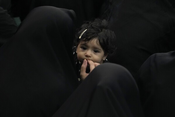 An Iranian Shiite Muslim woman feeds her child as they attend Ashoura mourning ritual, commemorating the 7th century martyrdom of Prophet Muhammad's grandson, Hussein, in the battle of Karbala in present-day Iraq, at the old main bazaar of Tehran, Iran, Tuesday, July 16, 2024. Shiites represent over 10% of the world's 1.8 billion Muslims and view Hussein as the rightful successor to the Prophet Muhammad. (AP Photo/Vahid Salemi)