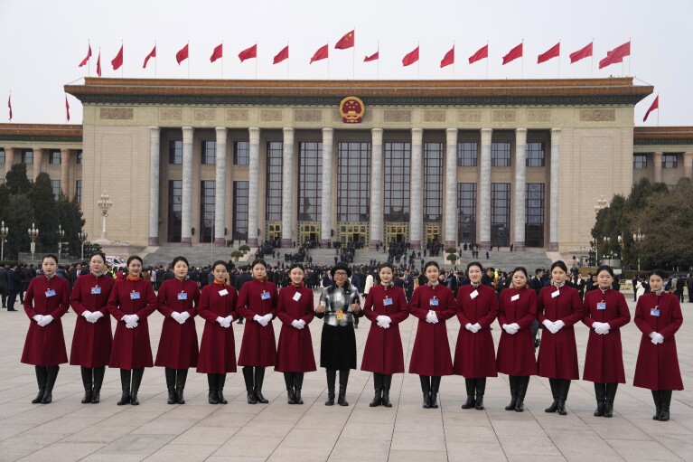 A Chinese journalist poses for photos with hosts before a preparatory session of the Chinese National People's Congress outside the Great Hall of the People in Beijing, Monday, March 4, 2024. (AP Photo/Ng Han Guan)