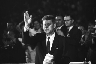 FILE - In this July 15, 1960, file photo, Sen. John F. Kennedy waves to the 65,000 persons who gathered in the Los Angeles Coliseum to hear him accept the Democratic nomination for U.S. President. The Olympic torch at Los Angeles Memorial Coliseum was lit Wednesday, July 15, 2020, to mark the 60th anniversary of John F. Kennedy's acceptance of the Democratic Party nomination for president at the historic stadium. Kennedy delivered what became known as "The New Frontier" speech on July 15, 1960, during the Democratic National Convention. The Coliseum hosted the 1932 and 1984 Olympics and Los Angeles is scheduled to hold a third Olympics in 2028. (AP Photo/File)