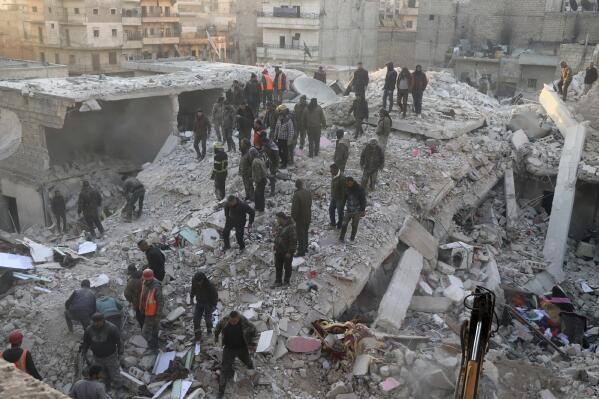In this photo provided by Kurdish-run Hawar News Agency, civil defense workers and civilians work on the rubble of a destroyed building in the Sheikh Maksoud neighborhood in Aleppo, Syria, Sunday, Jan. 22, 2023. The building collapsed in Aleppo early Sunday, killing at least 10 people, Syrian state media reported. (Hawar News Agency via AP)