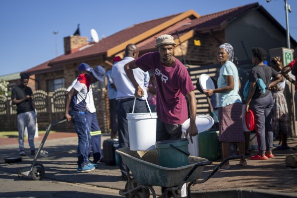 Residentes del municipio de Soweto, Sudáfrica, hacen cola para pedir agua el sábado 16 de marzo de 2024. Miles de sudafricanos hacen cola para pedir agua mientras la ciudad más grande del país, Johannesburgo, se enfrenta a un colapso sin precedentes de su sistema de agua, que afecta a millones de personas.  Los residentes ricos y pobres nunca han experimentado una escasez de esta gravedad.  (Foto AP/Jérôme Delay)