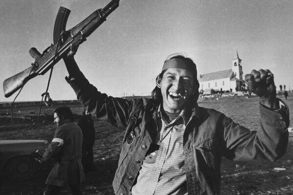 FILE - A man holds up a rifle in Wounded Knee, S.D., in February 1973. On Feb. 27, 1973, members of the American Indian Movement took over the town, starting a 71-day occupation on the Pine Ridge Indian Reservation in South Dakota. (AP Photo/Jim Mone, File)