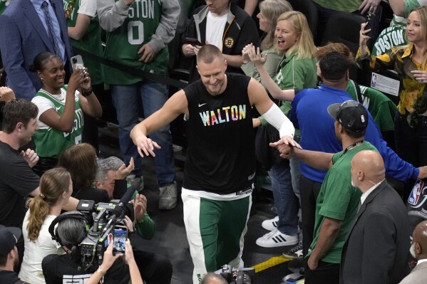 Boston Celtics center Kristaps Porzingis heads to the court while wearing a warmup shirt honoring basketball great Bill Walton before Game 1 of the basketball team's NBA Finals against the Dallas Mavericks, Thursday, June 6, 2024, in Boston. (AP Photo/Michael Dwyer)
