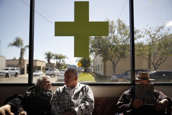 FILE - Kay Nelson, left, and Bryan Grode, retried seniors from Laguna Woods Village, chat in the lobby of Bud and Bloom cannabis dispensary while waiting for a free shuttle to arrive in Santa Ana, Calif., Feb. 19, 2019. (AP Photo/Jae C. Hong, File)
