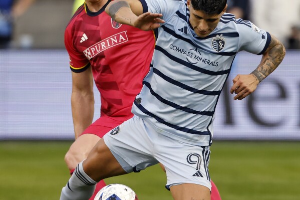 Sporting Kansas City forward Alán Pulido (9) is tripped by St. Louis City defender Tim Parker, left, during the first half of an MLS playoff soccer match, Sunday, Nov. 5, 2023, in Kansas City, Kan. (AP Photo/Colin E. Braley)