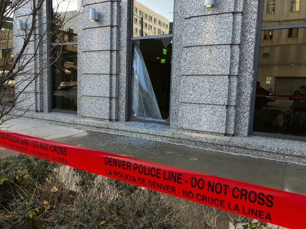 Police line tape marks a broken window at the the Ralph L. Carr Colorado Judicial Center, Tuesday, Jan. 2, 2024, in downtown Denver. A man shot through a window and broke into the Colorado Supreme Court building early Tuesday and caused "significant and extensive" damage in several areas of the building before surrendering to police, according to the Colorado State Patrol. (Hyoung Chang/The Denver Post via AP)