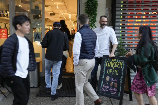Dominique Ansel, second from right, greets people who have been waiting in line for the opening of his namesake bakery in New York, Thursday, Sept. 28, 2023. In 2013, before most people knew the term “going viral,” the French pastry chef created the Cronut, a cross between a croissant and a doughnut, at his newly opened New York bakery. (AP Photo/Seth Wenig)