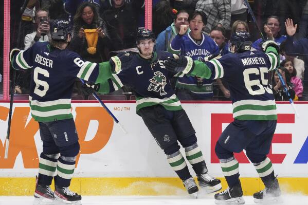 Vancouver Canucks' Brock Boeser, Bo Horvat and Ilya Mikheyev, from left, celebrate Horvat's second goal against the San Jose Sharks, during the third period of an NHL hockey game Tuesday, Dec. 27, 2022, in Vancouver, British Columbia. (Darryl Dyck/The Canadian Press via AP)