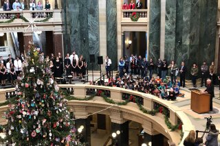 Wisconsin Gov. Tony Evers prepares to light the Wisconsin Capitol tree that he calls a "holiday tree" Friday, Dec. 6, 2019 in Madison, Wis. A choir sings songs including "O Christmas Tree" and "O Come All Ye Faithful" during the event. (AP Photo/Scott Bauer)