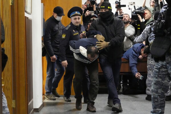 FILE - Saidakrami Murodali Rachabalizoda, a suspect in the Crocus City Hall shootings, is escorted by police and FSB officers in Basmanny District Court in Moscow, Russia, on March 24, 2024. The attack on the Moscow concert hall, the bloodiest assault on Russian soil in two decades, appears to be setting the stage for an increasingly harsh response by President Vladimir Putin. Four suspects in the attack appeared in court showing signs of brutal treatment while in custody. (AP Photo/Alexander Zemlianichenko, File)