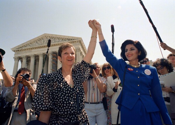 FILE - Norma McCorvey, Jane Roe in the 1973 court case, left, and her attorney Gloria Allred hold hands as they leave the Supreme Court building in Washington after sitting in while the court listened to arguments in a Missouri abortion case, April 26, 1989. (AP Photo/J. Scott Applewhite, File)