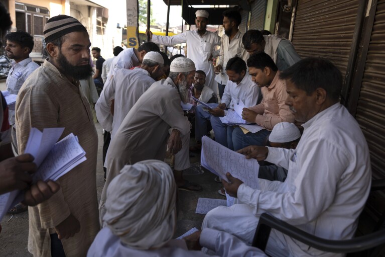 Muçulmanos verificam seus nomes em uma lista de eleitores ao chegarem para votar na vila de Nahal, estado de Uttar Pradesh, Índia, em 26 de abril de 2024. (AP Photo/Altaf Qadri)