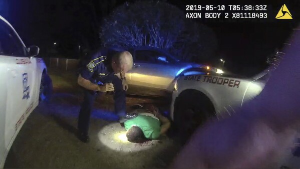 FILE - In this image from video from Louisiana state police state trooper Dakota DeMoss' body-worn camera, trooper Kory York bends over with his foot on Ronald Greene's shoulder after he was taken into custody on May 10, 2019, outside of Monroe, La. On Monday, Oct. 9, 2023, a judge delivered a victory to the state prosecution of white Louisiana lawmen in the deadly 2019 arrest of Ronald Greene, allowing the most serious charge of negligent homicide to go forward against York, captured on video dragging the Black motorist by his ankle shackles and forcing him to lie facedown in the dirt. (Louisiana State Police via AP, File)